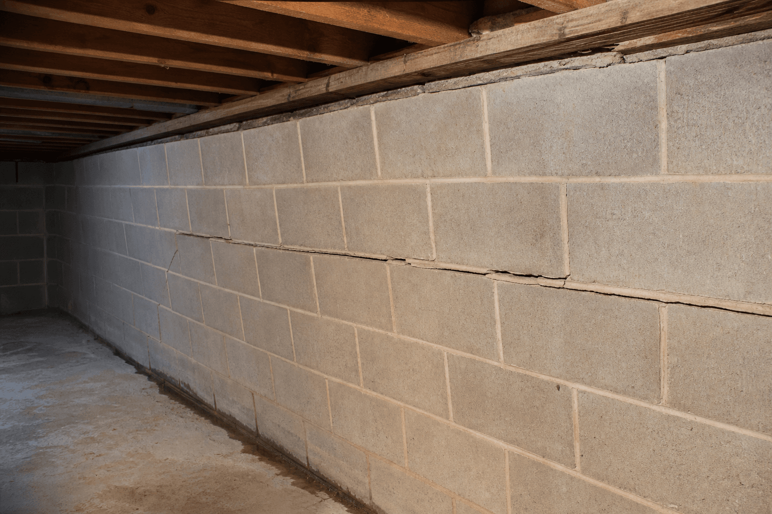 Concrete block foundation wall with a horizontal crack and inward bowing